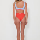 Person wearing a red bikini with a light blue bralette top on a white background