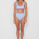 Woman wearing a light blue bikini with red accents on a white background