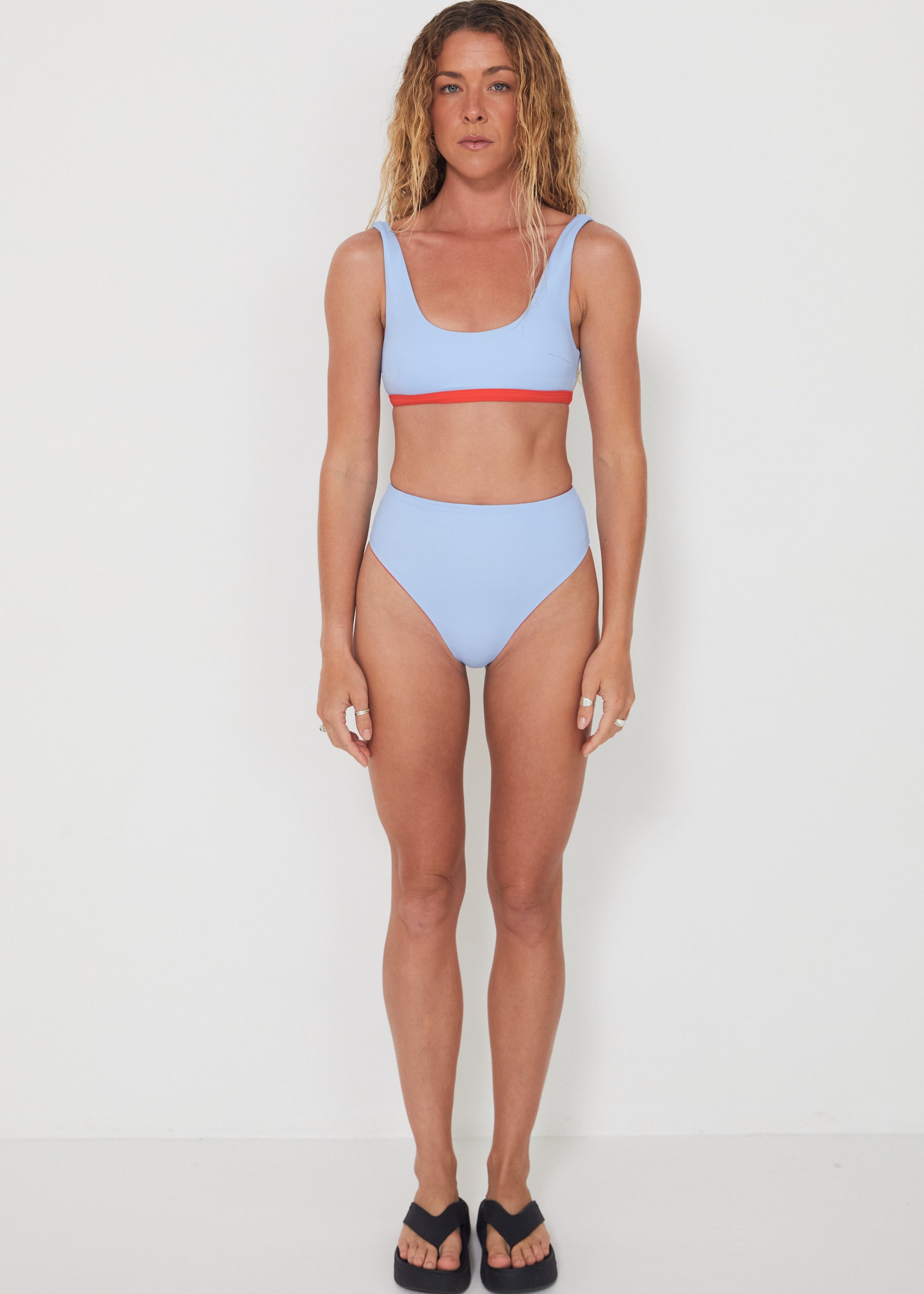 Woman wearing a light blue bikini with red accents on a white background