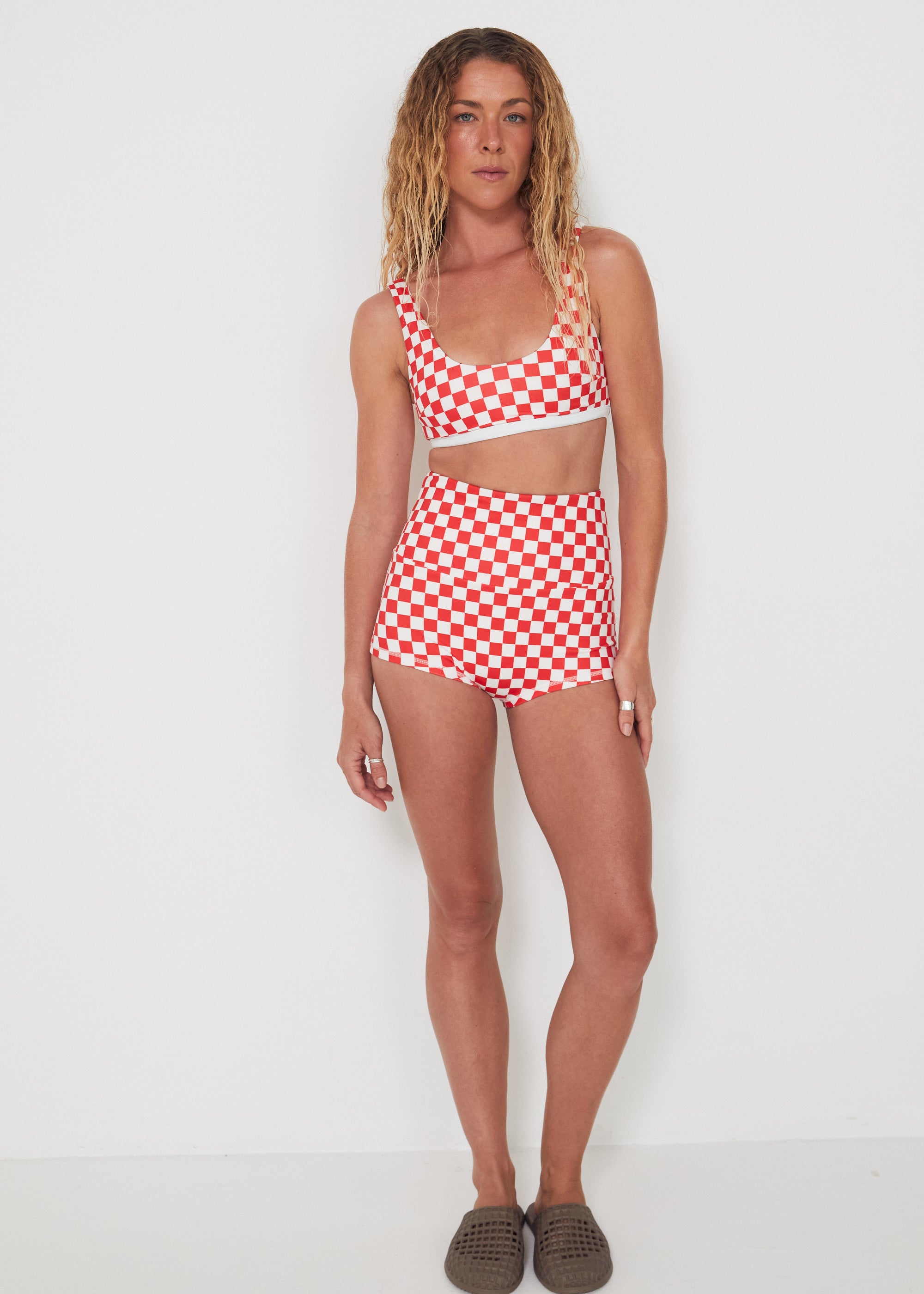 Woman wearing a red and white checkered bralette swim top and original betty bottoms on a white background
