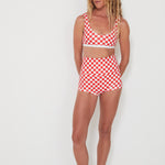 Woman wearing a red and white checkered punchy surf top and original betty bottoms outfit on a white background