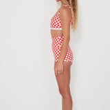 Woman wearing a red and white checkered bralette swim top and original betty bottoms on a white background