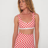 Woman wearing a red and white checkered two-piece swimsuit against a plain background