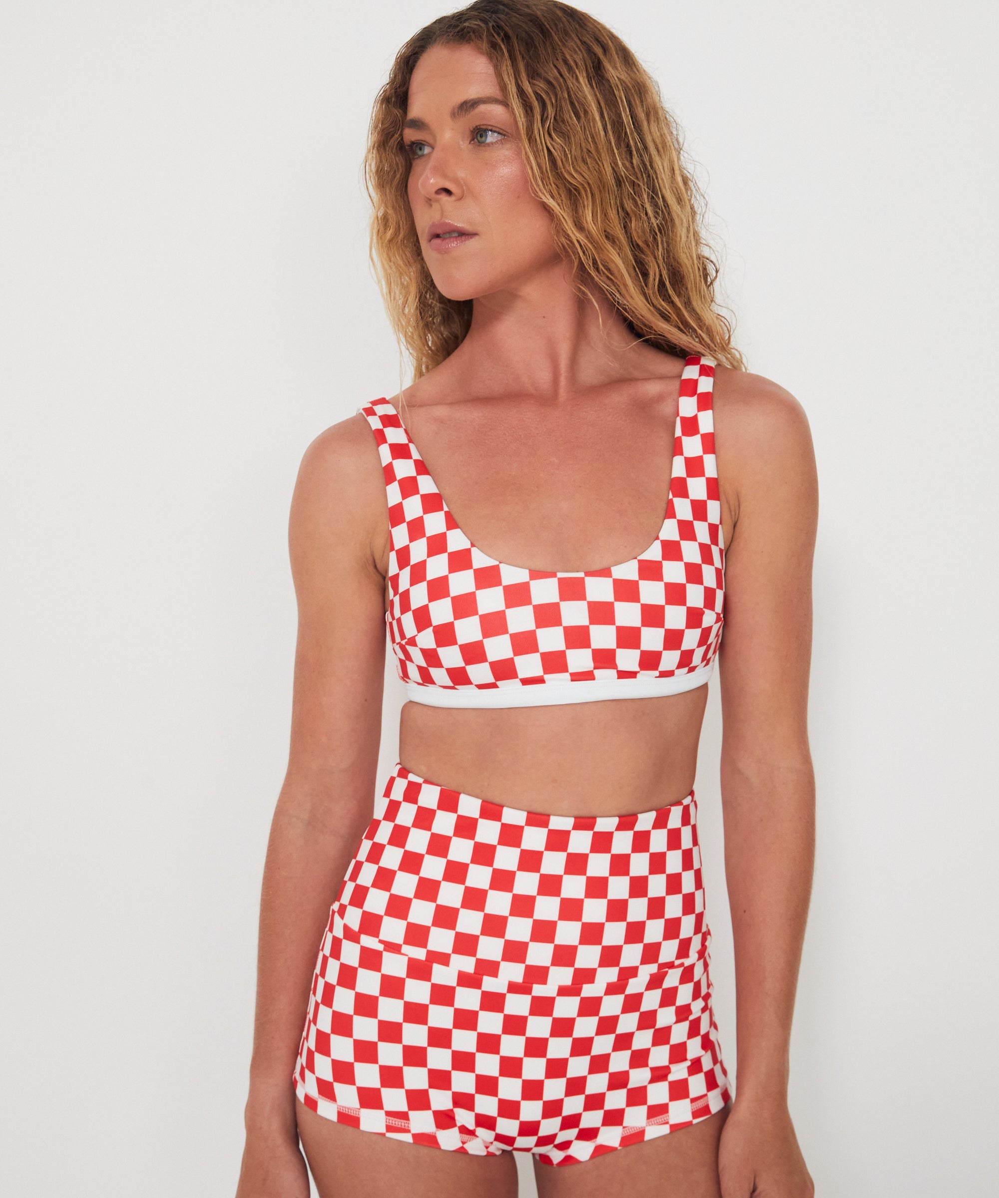 Woman wearing a red and white checkered two-piece swimsuit against a plain background