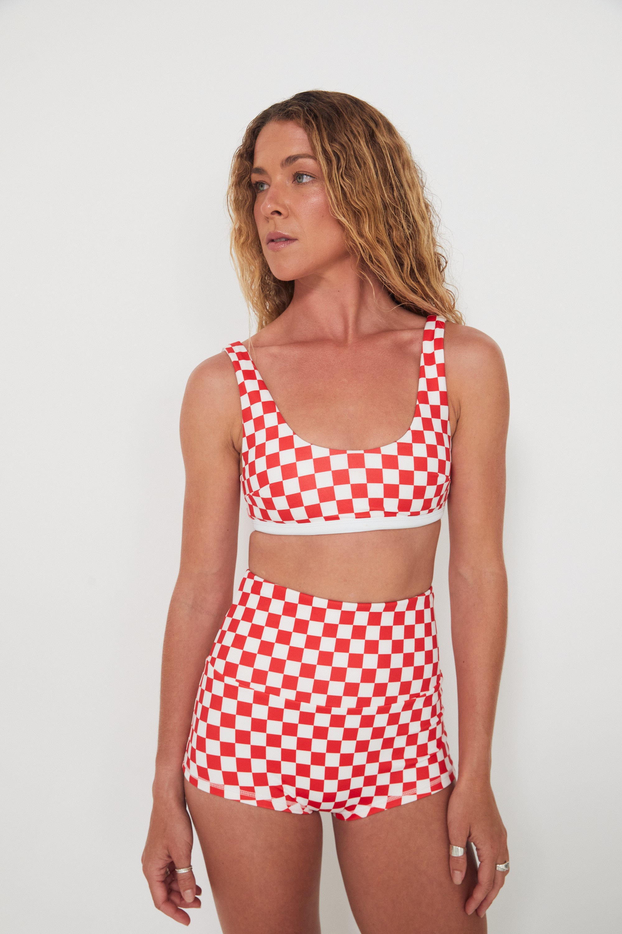 Woman wearing a red and white checkered two-piece swimsuit against a plain background