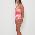 Woman wearing a red and white checkered swimsuit against a white background