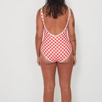 Person wearing a red and white checkered swimsuit against a white background