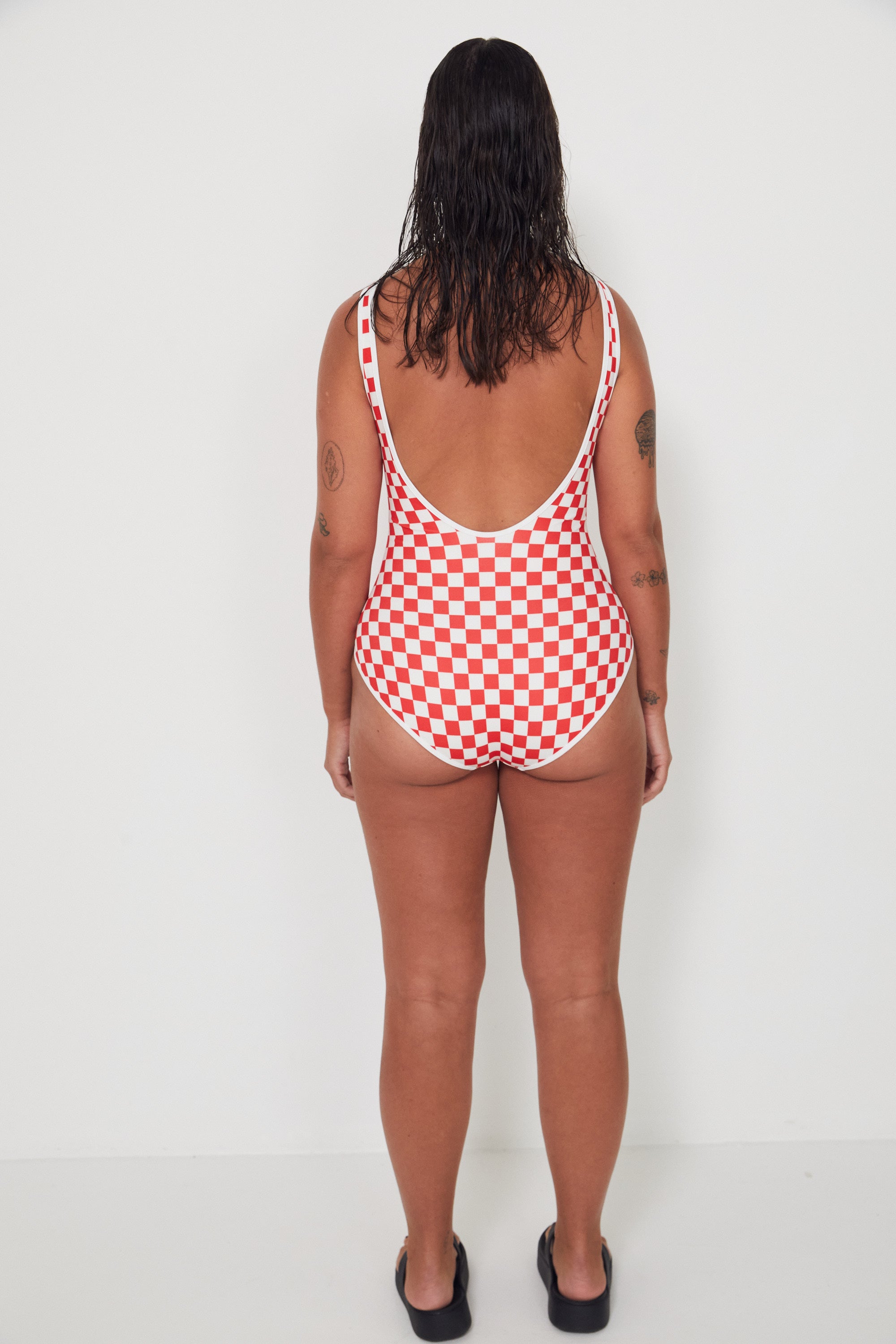Person wearing a red and white checkered swimsuit against a white background