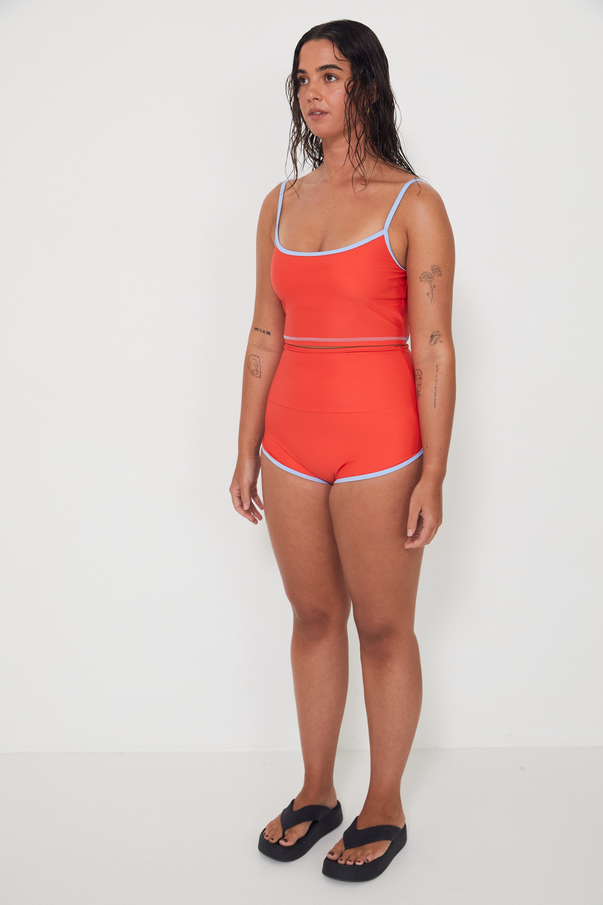 Woman wearing a red two piece swim set with blue trim on a white background