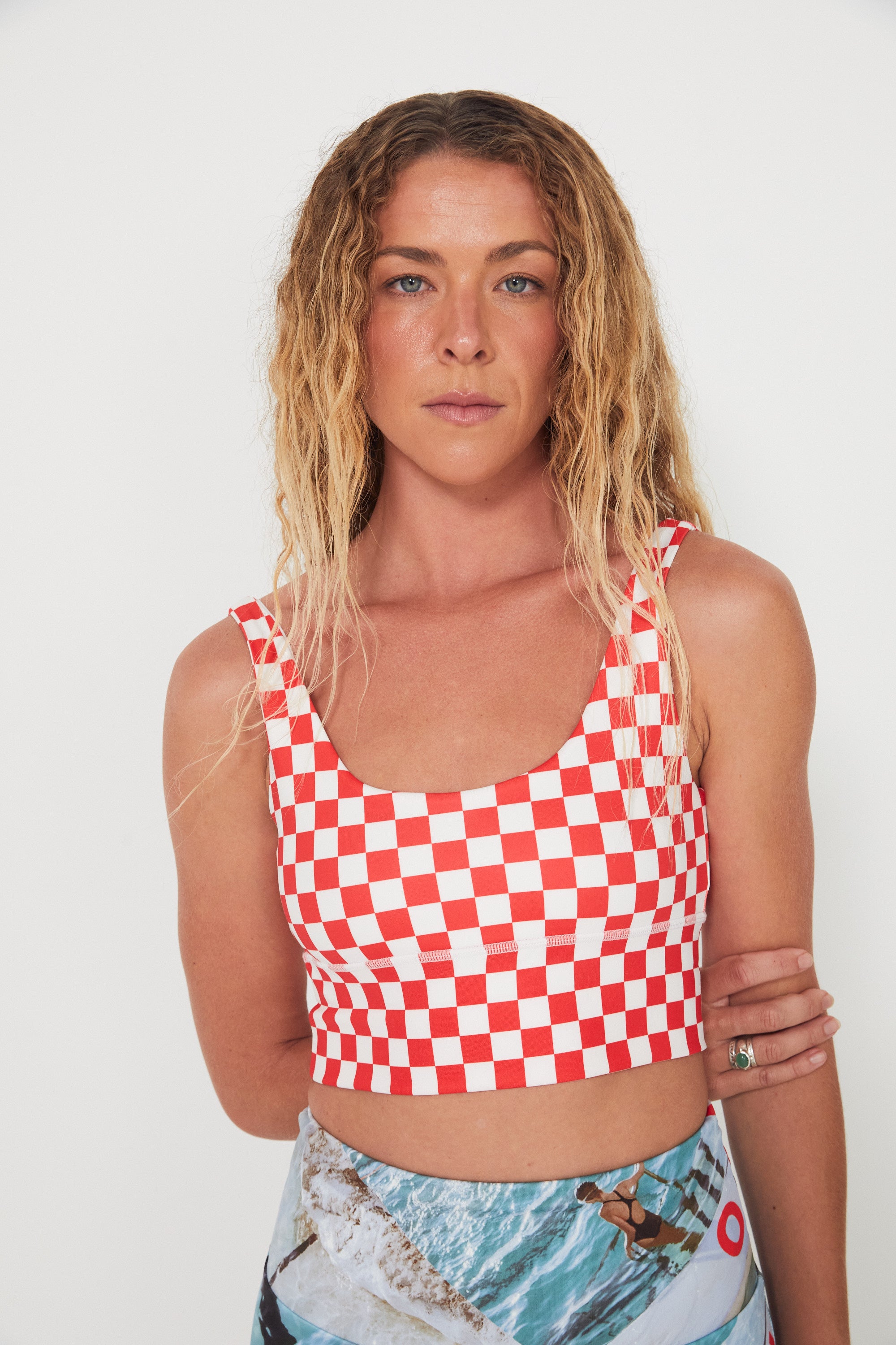 Woman wearing a red and white checkered punchy surf crop top against a white background