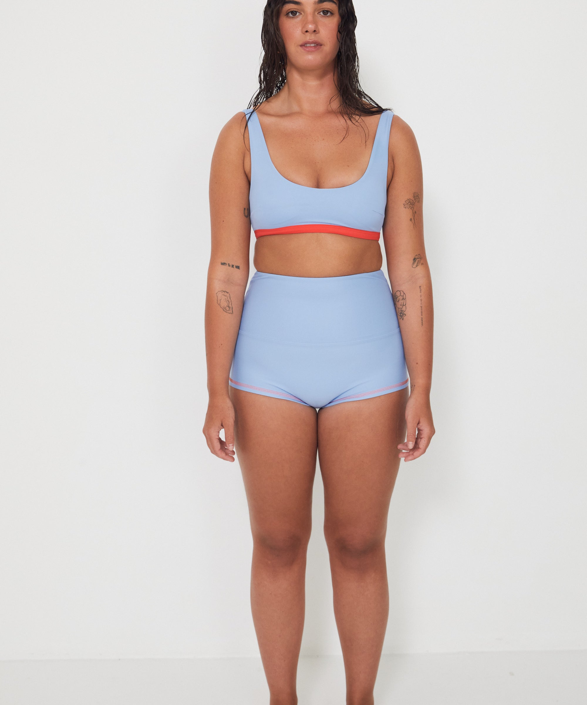 Woman wearing a light blue bralette bikini and original betty bottoms with a white background