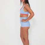 Woman wearing a light blue and red sports bra and shorts set on a white background