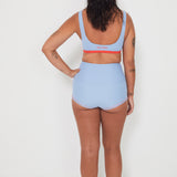 Person wearing a light blue sports bralette surf top bra and high-waisted original betty bottoms swim bottoms on a white background