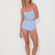 Woman wearing a baby blue tankini surf top and betty bottoms 2.0 with red trim on a white background