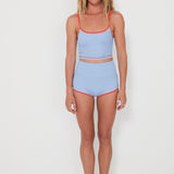 Woman wearing a light blue two-piece swimsuit with red trim on a white background