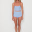 Woman wearing a light blue two-piece swimsuit with red trim on a white background