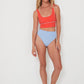 Woman wearing a red punchy surf top and light blue high-waisted drifer bikini bottoms on a white background
