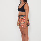 Woman wearing a black and white bralette by salt gypsy and boardsports with a vacay colorful patterned by salt gypsy and friday on a white background