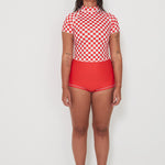 Person wearing a red and white checkered low rider rashugard top and red original betty bottoms shorts on a white background