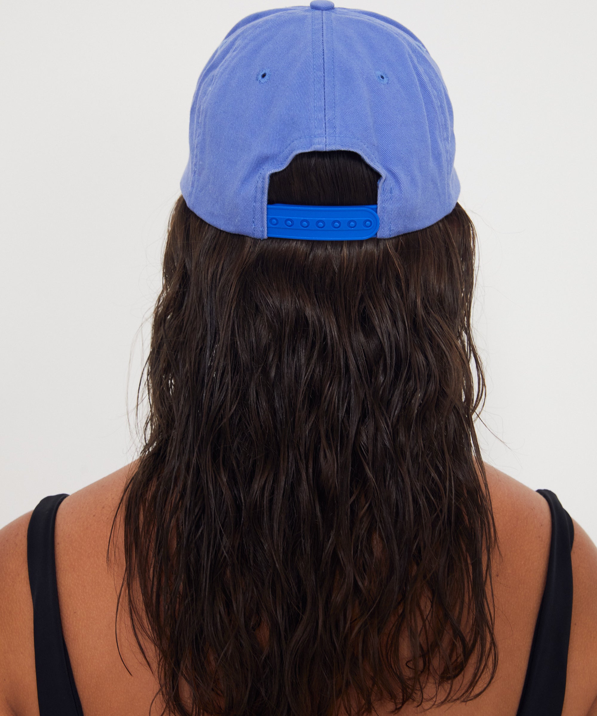 Person wearing a blue dad cap from behind on a white background