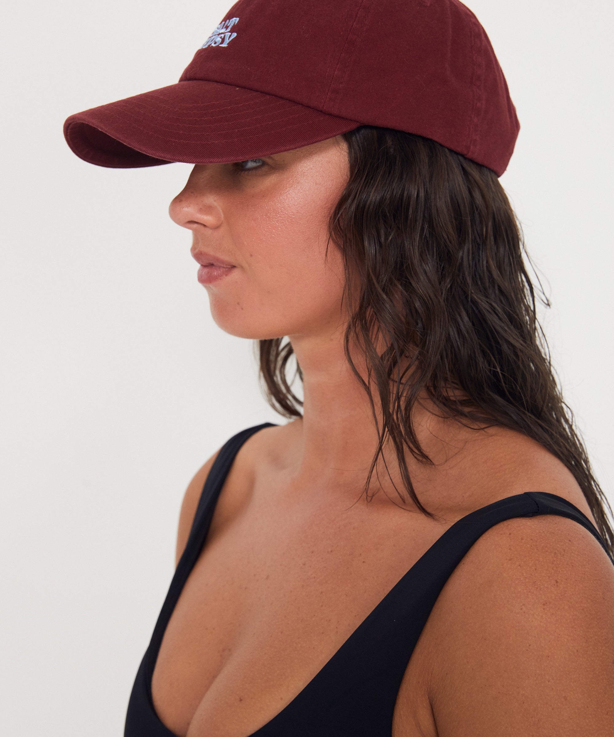 Woman wearing a maroon baseball dad cap on a white background