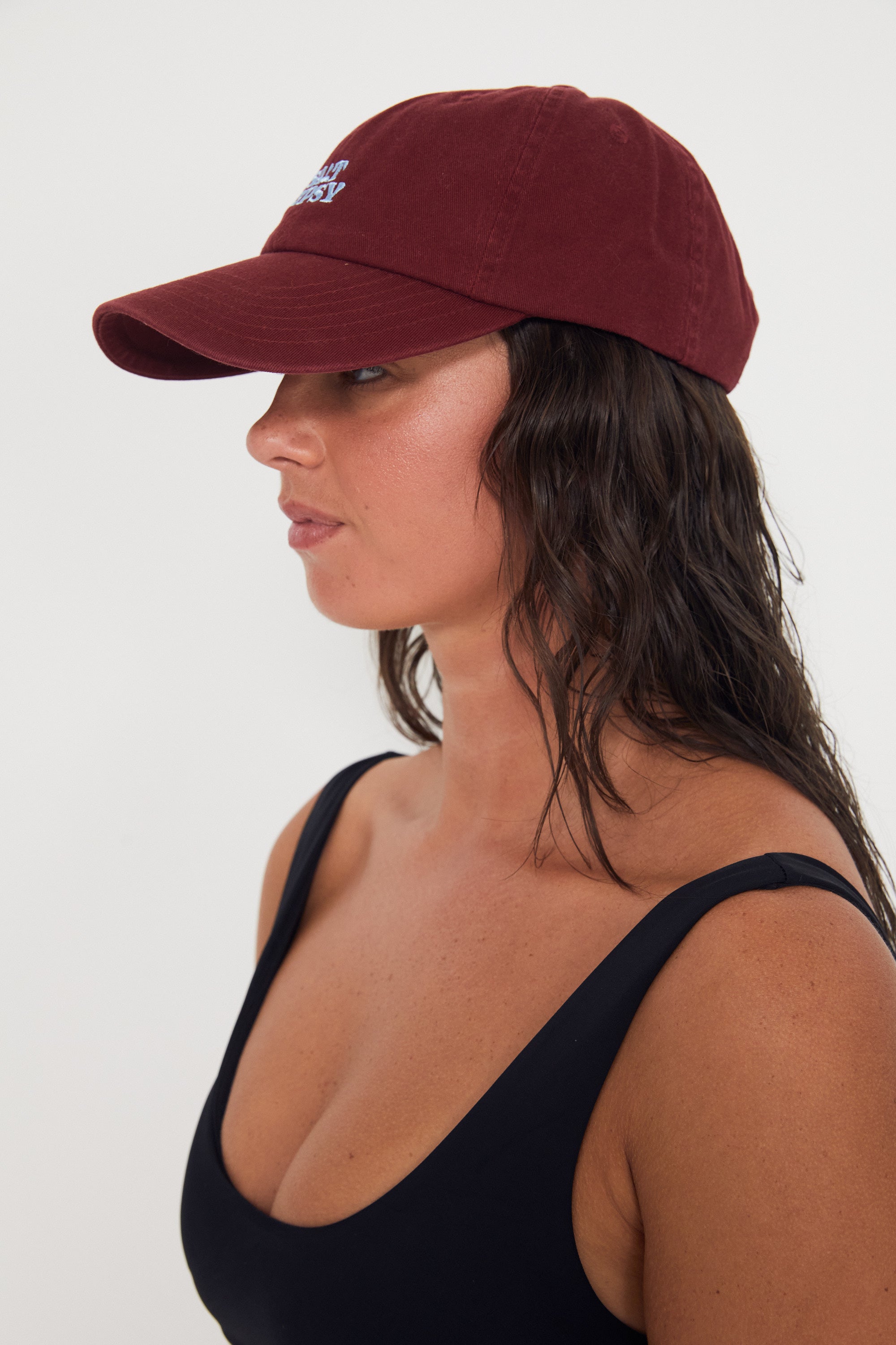 Woman wearing a maroon baseball dad cap on a white background