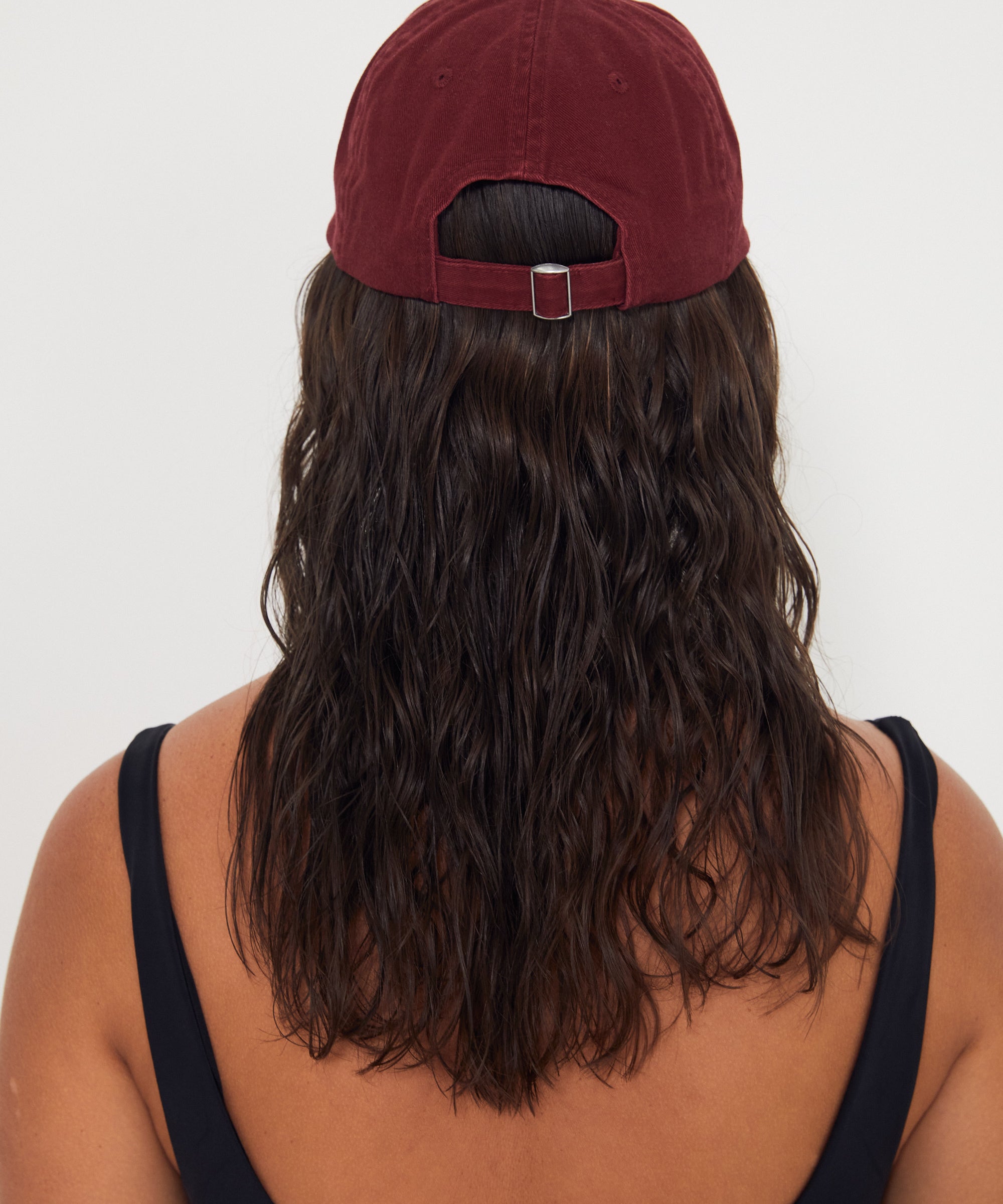 Person wearing a maroon cap and black tank top with 'Salt Gypsy' branding on a white background