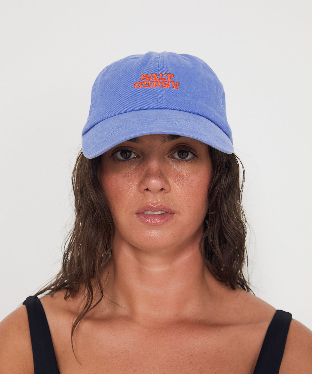Woman wearing a blue dad cap with a red 'Salt Gypsy' logo on a white background