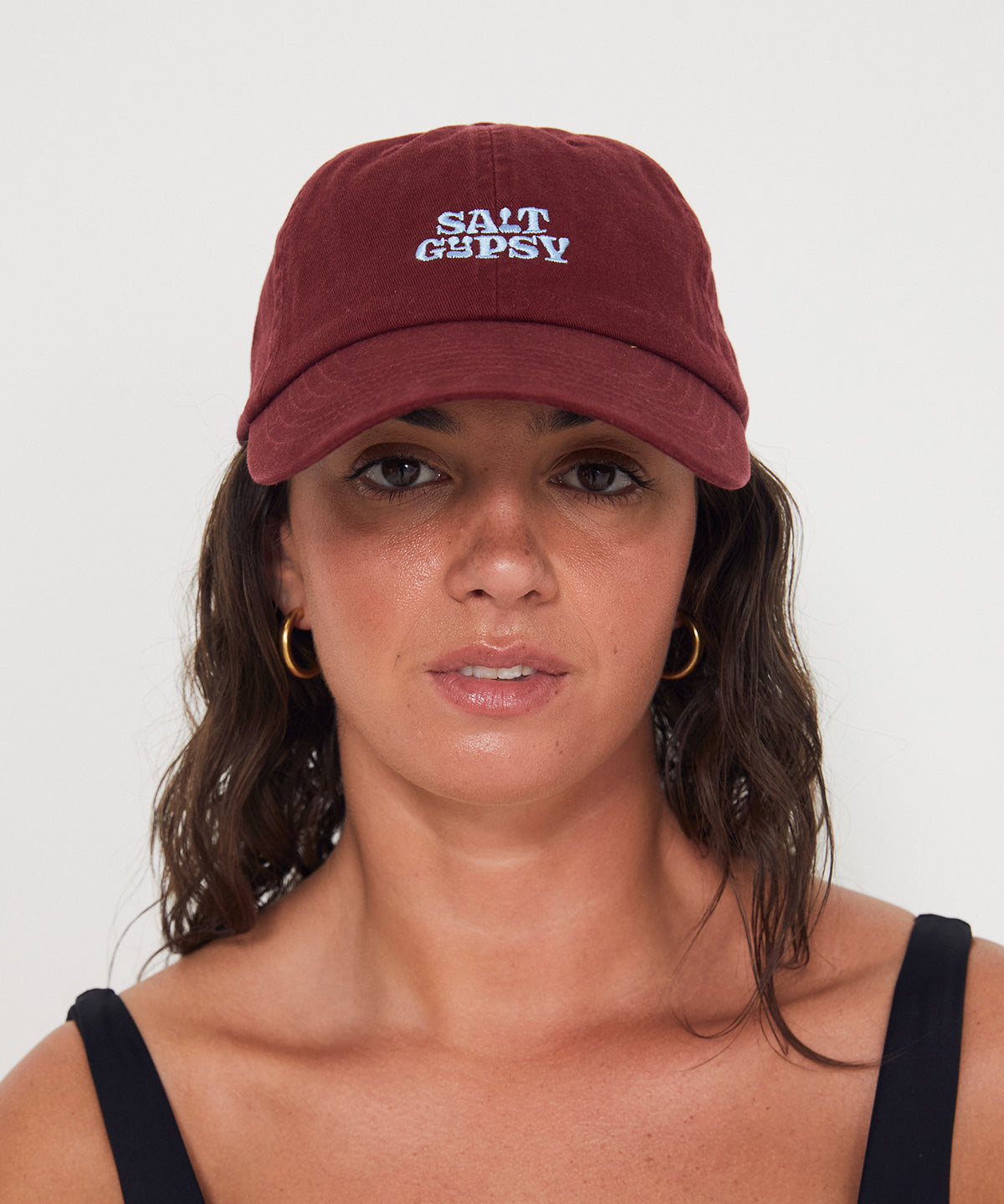 Woman wearing a maroon cap with a blue 'Salt Gypsy' logo on a white background
